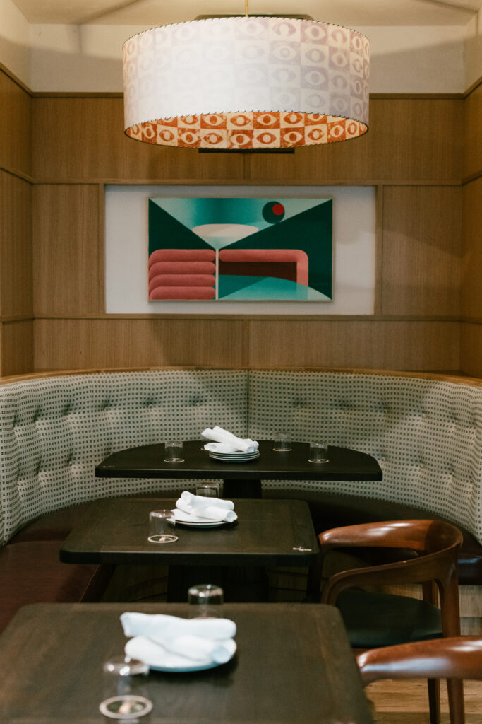 Interior of Nic + Junior’s restaurant in River North, Chicago, featuring accordion-style windows, woven leather seating, and a refined design-forward atmosphere.