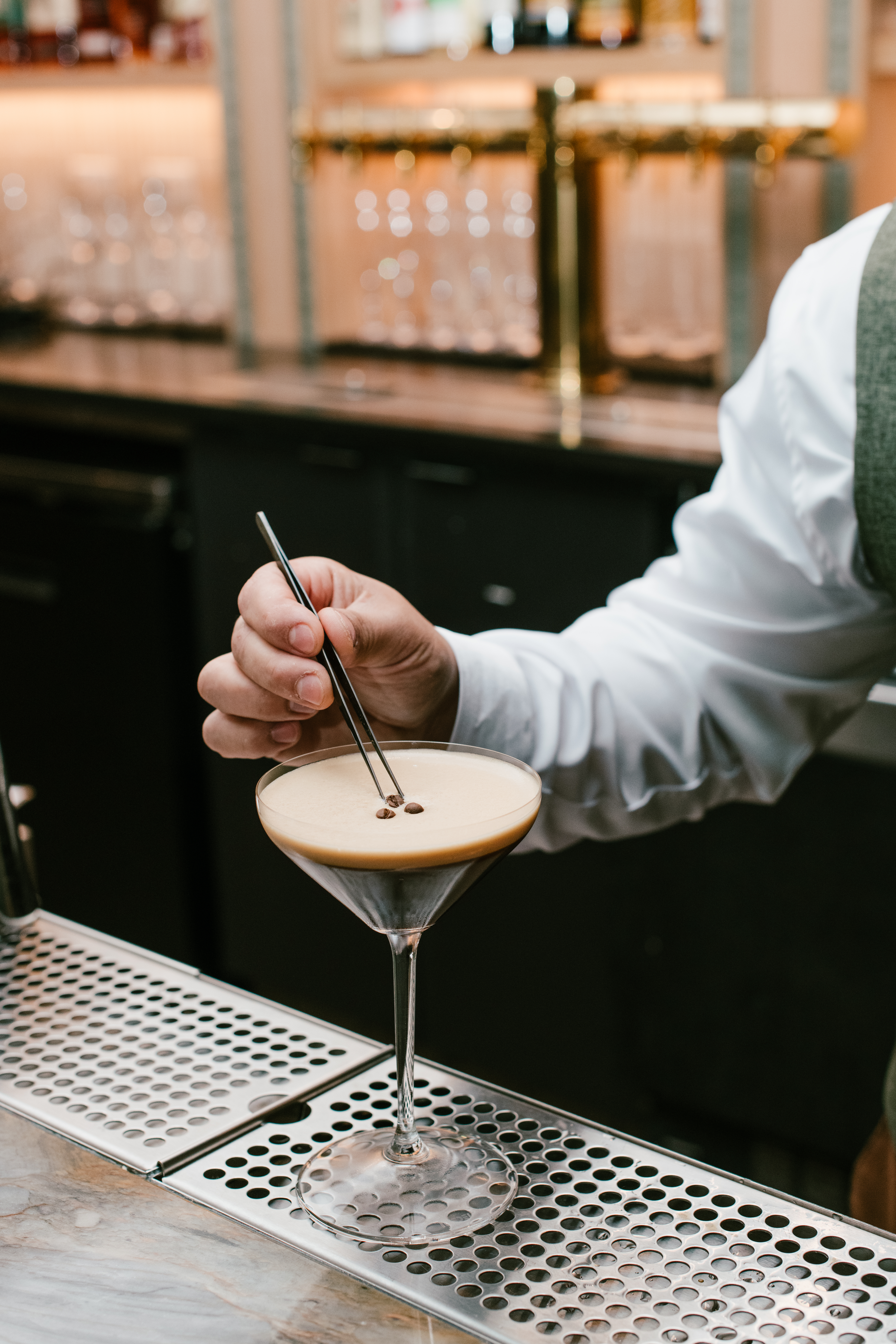 Bartender garnishing an espresso martini with coffee beans at Nic + Junior’s in River North, Chicago