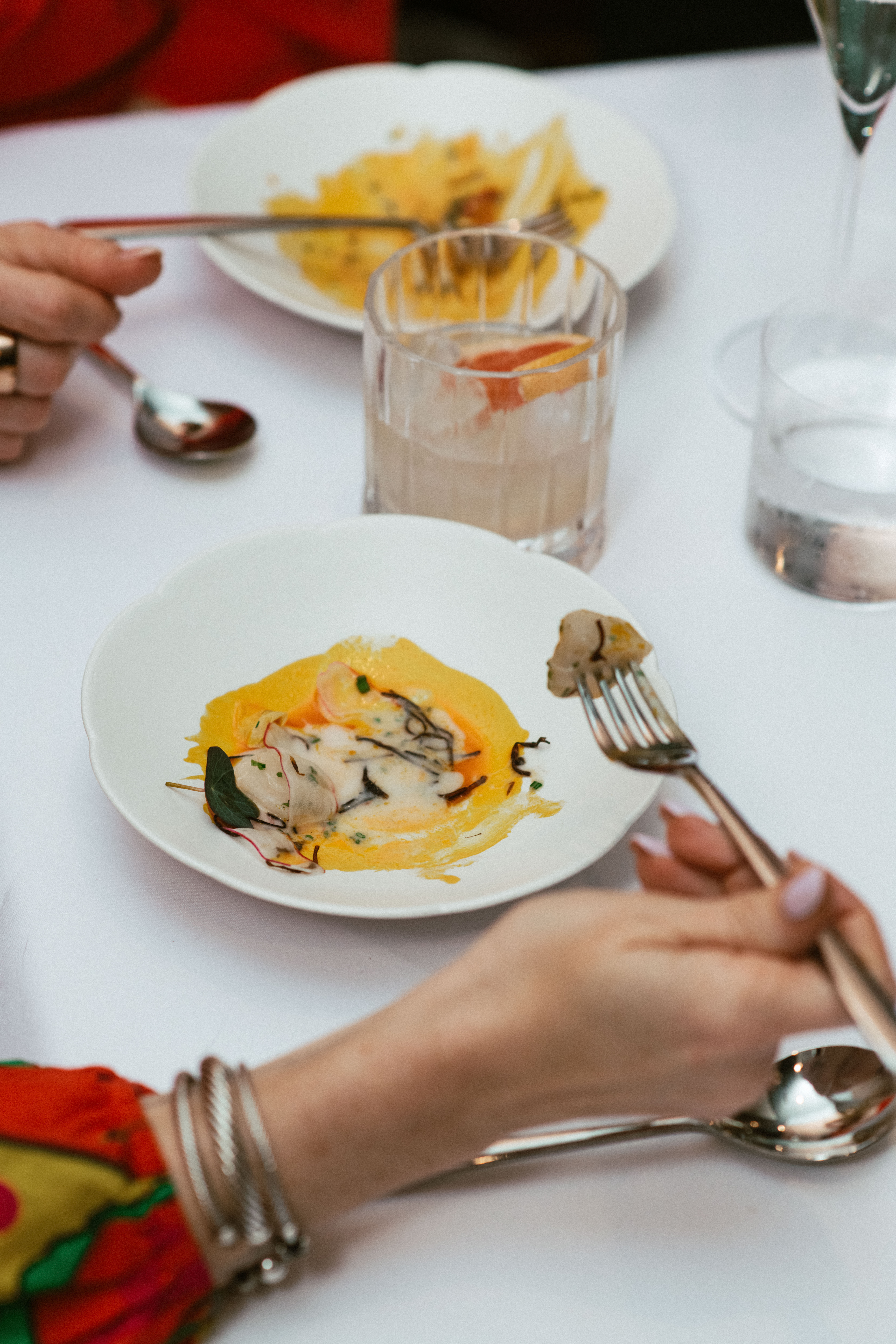 Guest enjoying a smoked scallop dish from the tasting menu at Nic + Junior’s, highlighting an immersive River North dining experience.