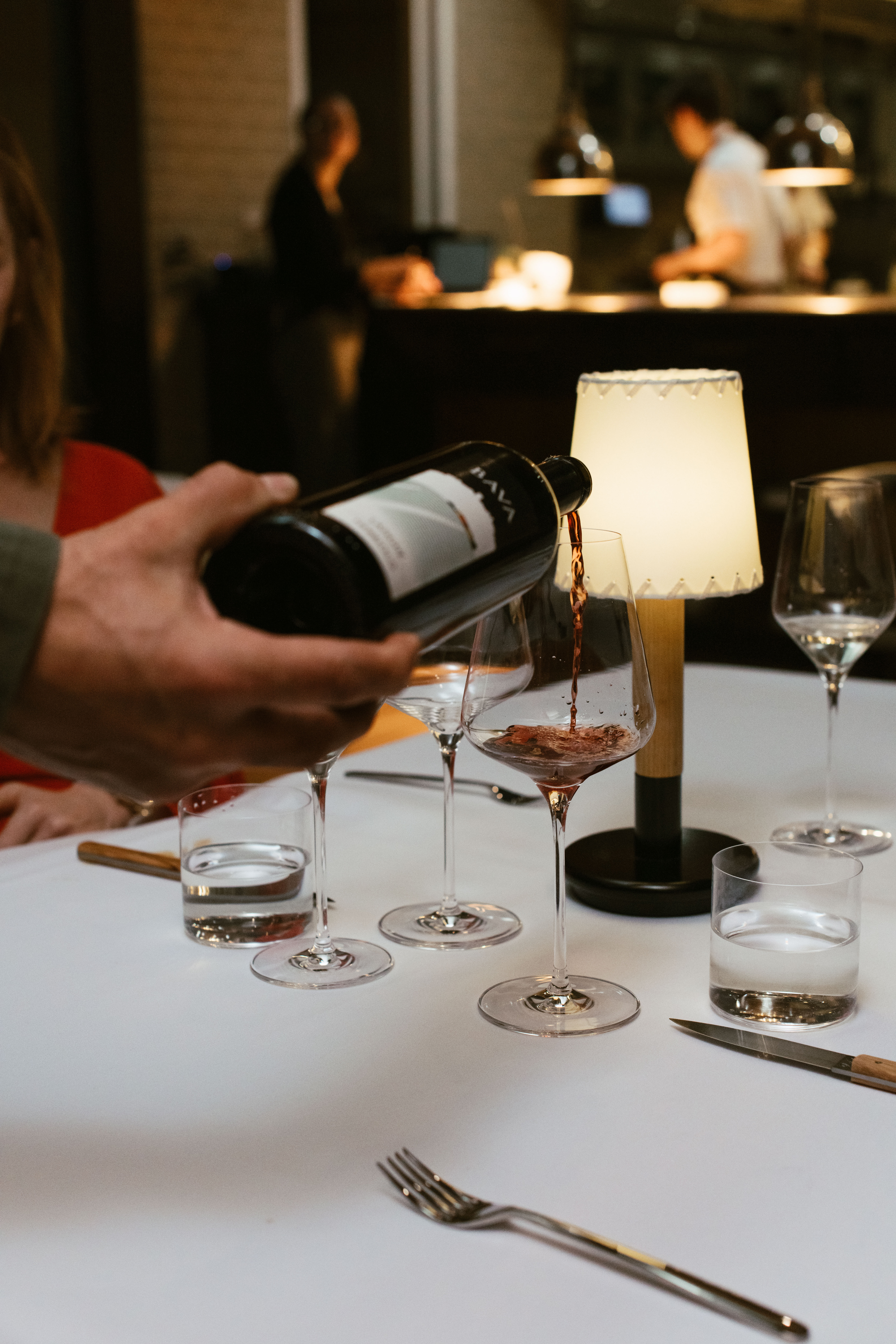 Server pouring red wine into a glass at Nic + Junior’s in River North, Chicago during dinner service