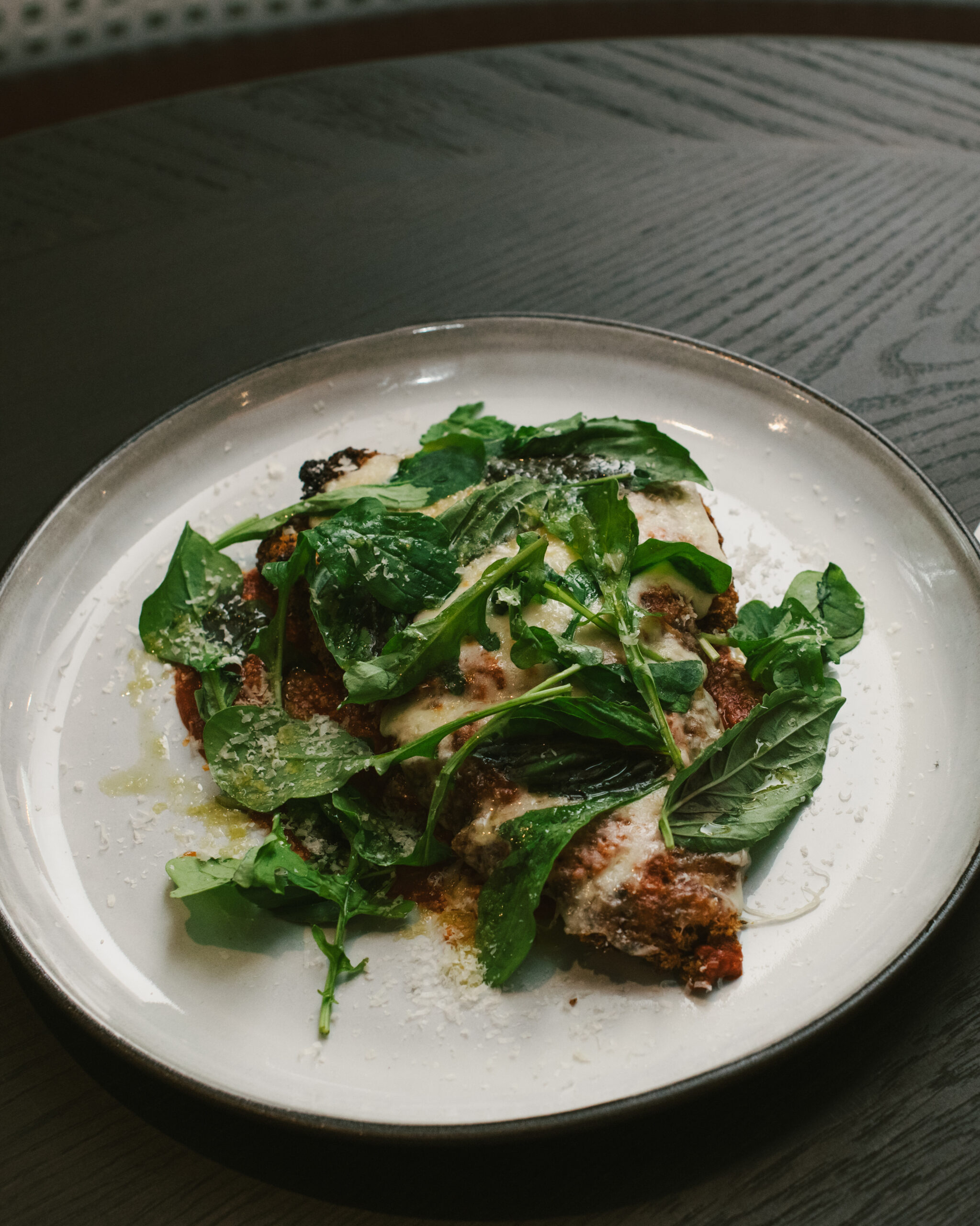Chicken Piri Piri Parmesan topped with fresh greens at Nic + Junior’s in River North, Chicago