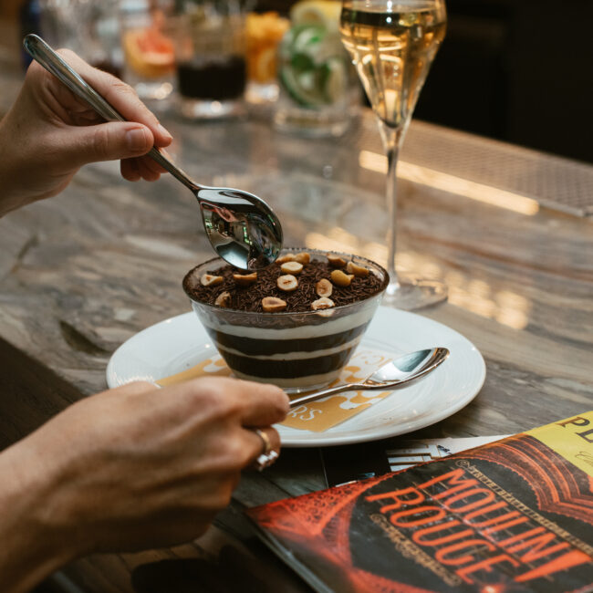 Brigadeiro tiramisu dessert topped with hazelnuts, served with sparkling wine at the Nic + Junior’s bar
